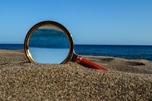 closeup-shot-loupe-magnifying-glass-sandy-beach.jpg