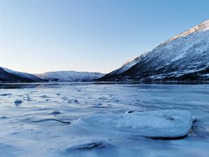 frozen-lake-by-snow-covered-hills-kattfjorden-norway-captured-during-daytime.jpg
